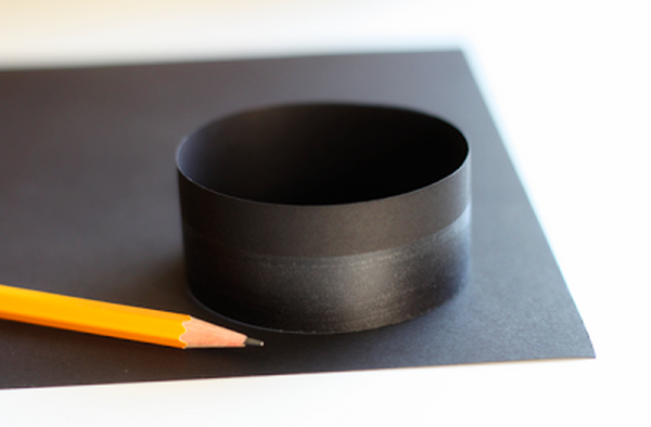 Sau đó, đặt ống giấy này vào một mảnh giấy màu đen và lấy bút chì vẽ xung quanh. Cắt hình tròn đã đánh dấu.