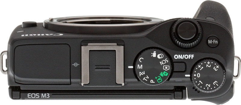 Từ trái qua: Flash “cóc”, đế gắn Flash rời (đã đậy nắp), bánh xe chọn chế độ chụp, nút bật tắt, bánh xe bù sáng. phía trên: vòng xoay chính (chỉnh tốc khẩu v..v, nút chụp, nút M.Fn để gán chức năng tùy ý.